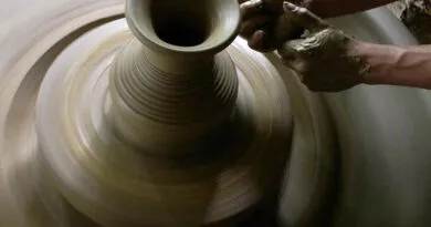 duas mãos moldando vaso de barro