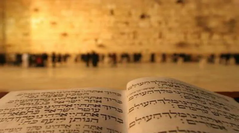 Bíblia em hebraico aberta e muro das lamentações ao fundo
