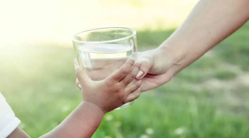 pessoa dando um copo de água para uma criança