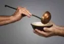mão com uma concha colocando alimento em uma tigela