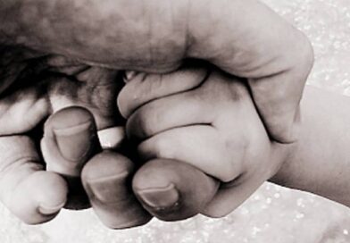 Uma mão adulta segurando a mão de uma criança